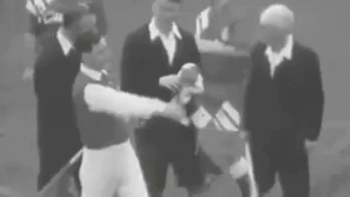 A Group Of Men In Suits Are Standing Around A Baseball Player . GIF