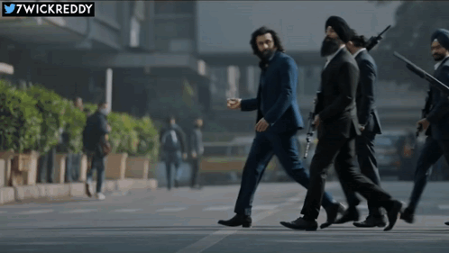 A Group Of Men In Suits Are Walking Down A Street With A Twitter Logo In The Corner GIF