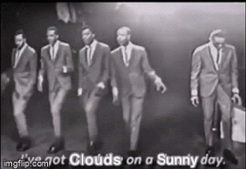 A Group Of Men In Suits Are Walking In A Row . GIF