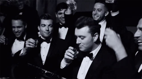 A Group Of Men In Tuxedos And Bow Ties Are Drinking And Smoking GIF