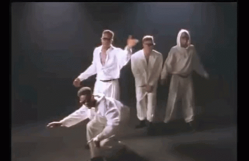A Group Of Men In White Clothes Are Dancing Together On A Stage . GIF