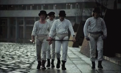 A Group Of Men In White Shirts And Hats Are Walking Down A Street . GIF
