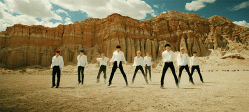 A Group Of Men In White Shirts Are Standing In A Desert GIF