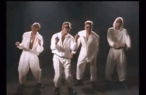 A Group Of Men In White Suits Are Dancing In A Line . GIF
