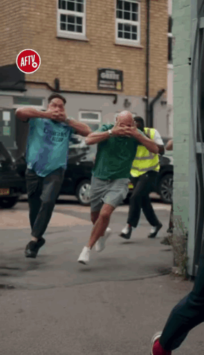 A Group Of Men Running Down A Street With A Red Sign That Says Aftv GIF