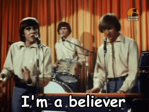A Group Of Men Singing Into Microphones With The Words " I 'M A Believer " Written On The Bottom GIF
