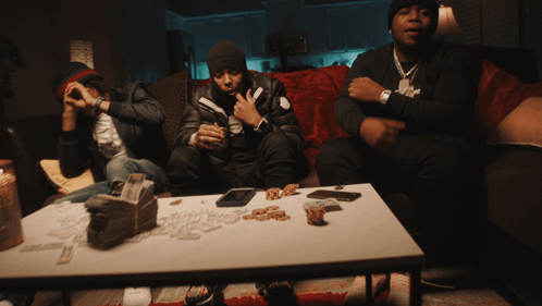 A Group Of Men Sit On A Couch With A Table Full Of Money GIF