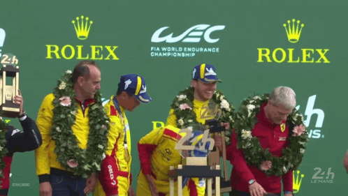 A Group Of Men Stand On A Podium With Rolex Advertisements Behind Them GIF