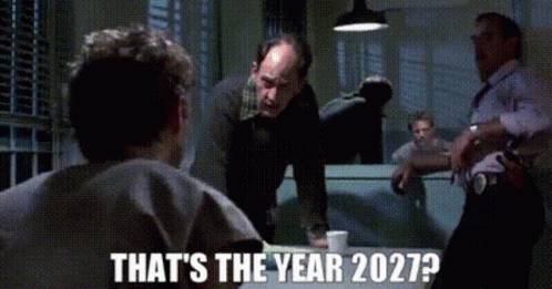 A Group Of Men Standing Around A Table With The Words " That 'S The Year 2027 " On The Bottom GIF