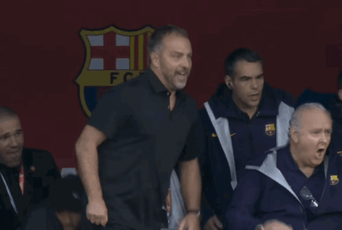 A Group Of Men Standing In Front Of A Sign That Says ' Fcb ' On It GIF