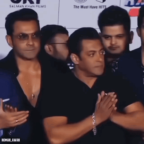 A Group Of Men Standing In Front Of A Sign That Says ' Salman Khan Films ' GIF