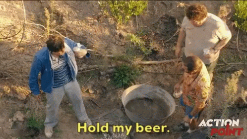 A Group Of Men Standing In The Dirt With The Words Hold My Beer On The Bottom GIF