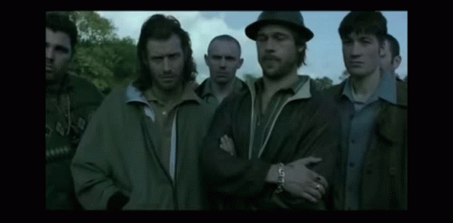 A Group Of Men Standing Next To Each Other In A Dark Room GIF