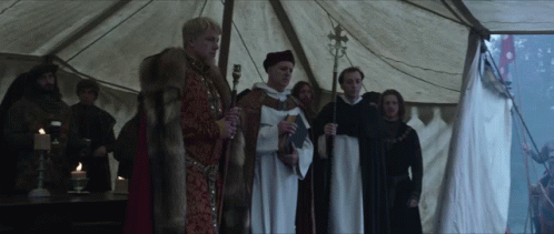 A Group Of Men Standing Under A Tent Holding Candles And A Cross GIF