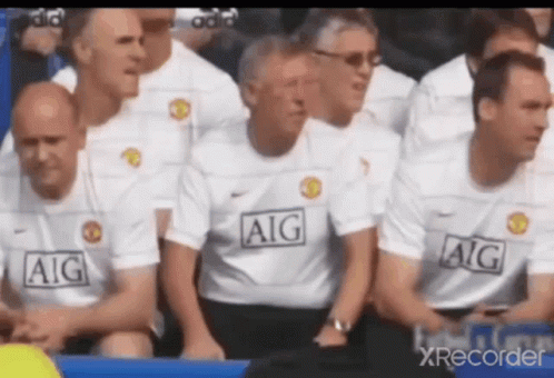 A Group Of Men Wearing Aig Shirts Are Sitting In The Stands . GIF