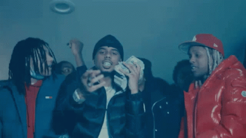 A Group Of Men Wearing Hooded Jackets Are Sitting In A Dark Room . GIF