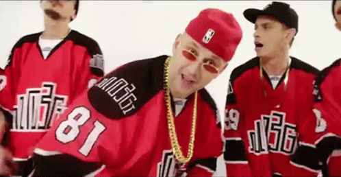 A Group Of Men Wearing Red And Black Hockey Jerseys And Hats Are Standing Next To Each Other . GIF