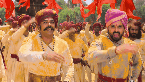 A Group Of Men Wearing Turbans And Yellow Shirts Are Dancing GIF