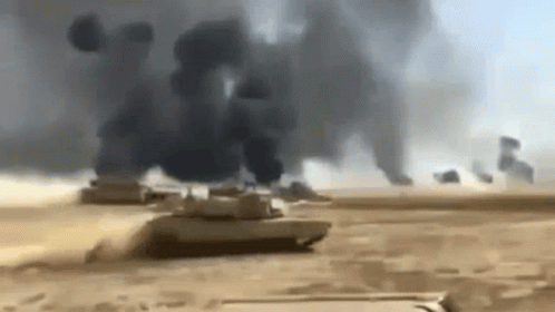A Group Of Military Tanks Are Driving Through A Desert . GIF