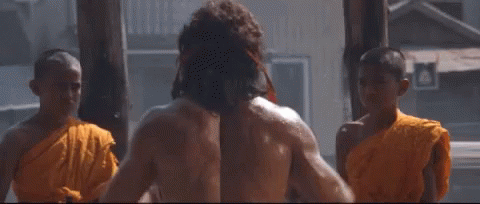 A Group Of Monks Are Standing Around A Shirtless Man Washing His Hair . GIF