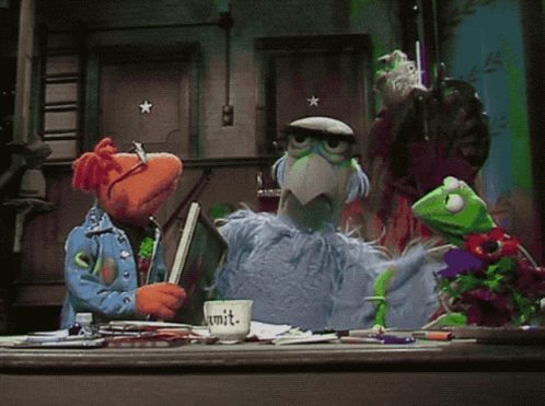 A Group Of Muppets Are Gathered Around A Desk With A Cup That Says Commit On It GIF