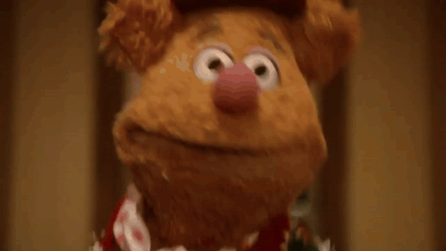 a group of muppets are standing in a hallway and one of them is wearing a sweater that says muppets
