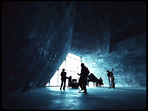 A Group Of Musicians Are Standing In A Dark Room With The Number 11 On The Wall Behind Them GIF