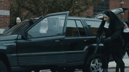 A Group Of Nuns Are Standing In Front Of A Black Grand Cherokee GIF