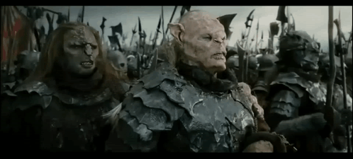 A Group Of Orcs Are Standing Next To Each Other In A Field Holding Spears . GIF