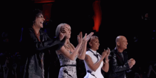 A Group Of People Are Applauding On A Stage . GIF