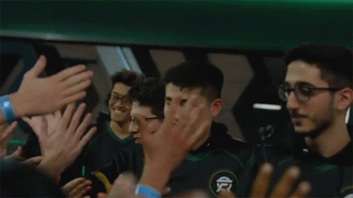 A Group Of People Are Clapping And Applauding A Man In A Green Shirt GIF