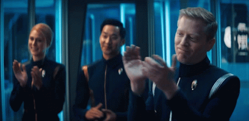 A Group Of People Are Clapping In Front Of A Sign That Says ' Exit ' GIF