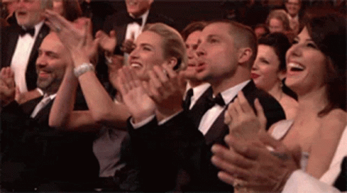 A Group Of People Are Clapping Their Hands In A Crowd . GIF
