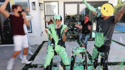 A Group Of People Are Covered In Green Slime With A Yellow Circle With The Letter N On It GIF
