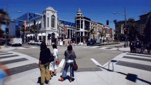 A Group Of People Are Crossing A Street In Front Of A Building That Says ' O'neill ' On It GIF