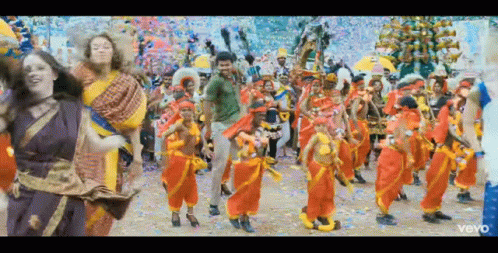 A Group Of People Are Dancing In A Colorful Parade . GIF