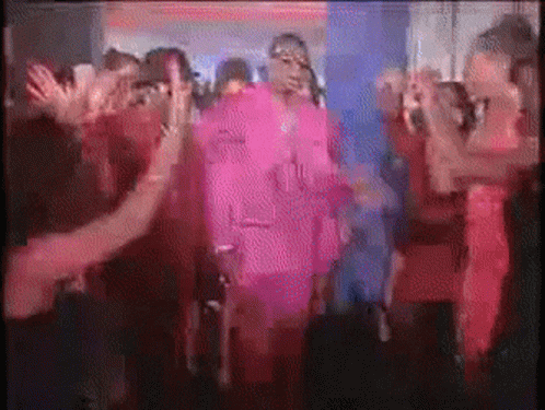 A Group Of People Are Dancing In A Dark Room And One Of Them Is Wearing A Pink Outfit GIF