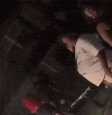 A Group Of People Are Dancing In A Dark Room While A Man Holds A Microphone . GIF