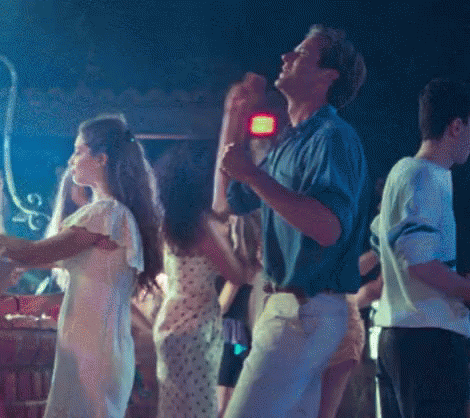 A Group Of People Are Dancing In A Dark Room With A Blue Light Behind Them GIF