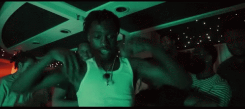 A Group Of People Are Dancing In A Dark Room With A Green Light Behind Them GIF