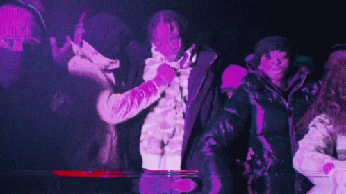 A Group Of People Are Dancing In A Dark Room With Purple Lights Behind Them . GIF