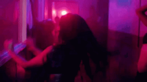 A Group Of People Are Dancing In A Dark Room With Purple Lights . GIF