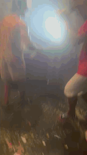 A Group Of People Are Dancing In A Dark Room With Smoke Coming Out Of The Ceiling . GIF
