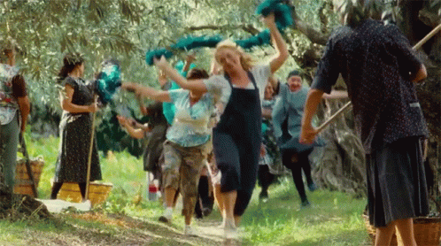 A Group Of People Are Dancing In A Field And One Woman Is Wearing Overalls GIF