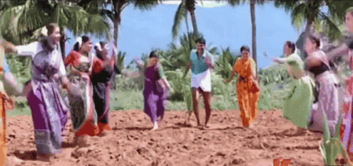 A Group Of People Are Dancing In A Field With A Man In A Blue Shirt GIF