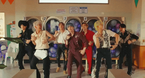 A Group Of People Are Dancing In A Laundromat With Numbers 1 2 3 4 And 5 On The Washers GIF