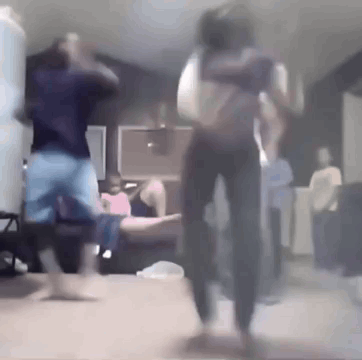 A Group Of People Are Dancing In A Living Room While A Man Holds A Baby . GIF