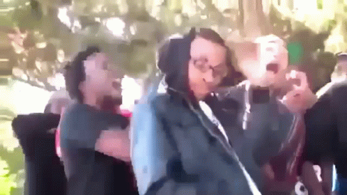 A Group Of People Are Dancing In A Park And One Of Them Is Wearing A Hoodie GIF
