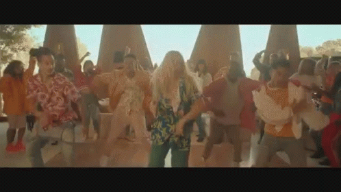 A Group Of People Are Dancing In A Park In Front Of A Large Group Of People . GIF