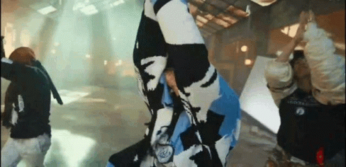 A Group Of People Are Dancing In A Room While A Man Is Holding A Flag . GIF